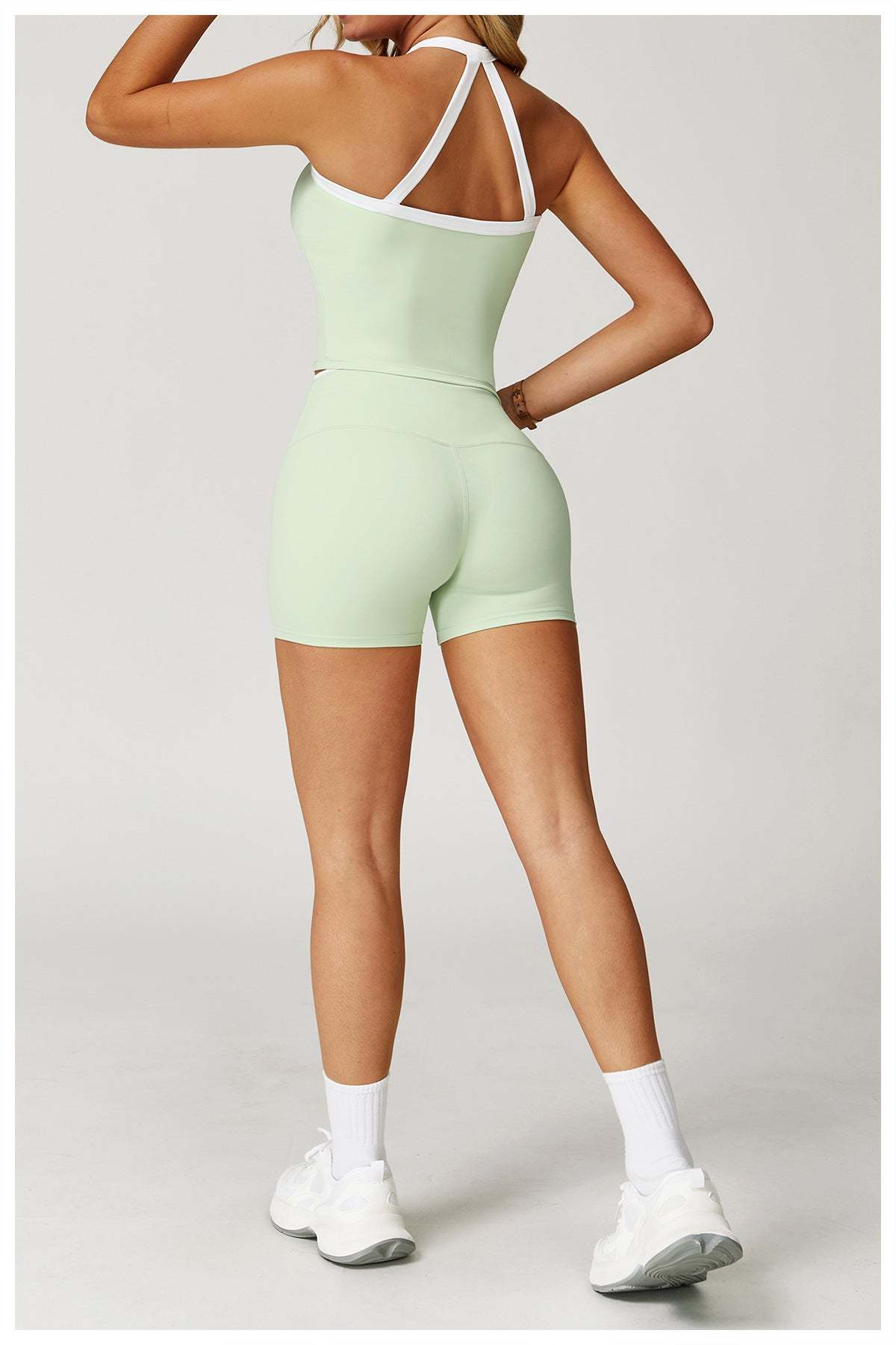 Woman wearing high-waist gym shorts and sports top in light green for active streetwear workout